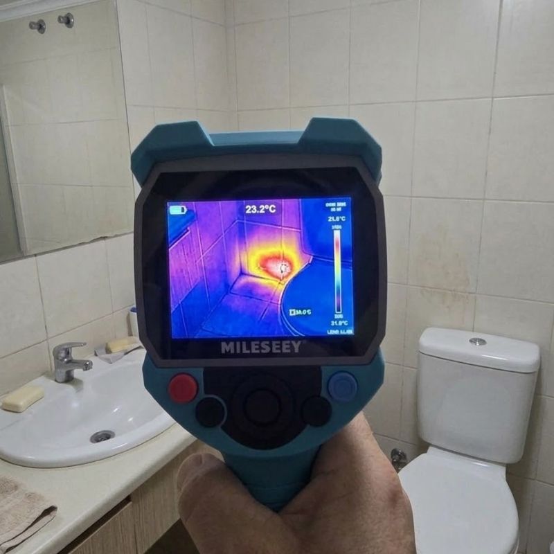 Thermal imaging device locating hidden bathroom leak beside toilet and vanity